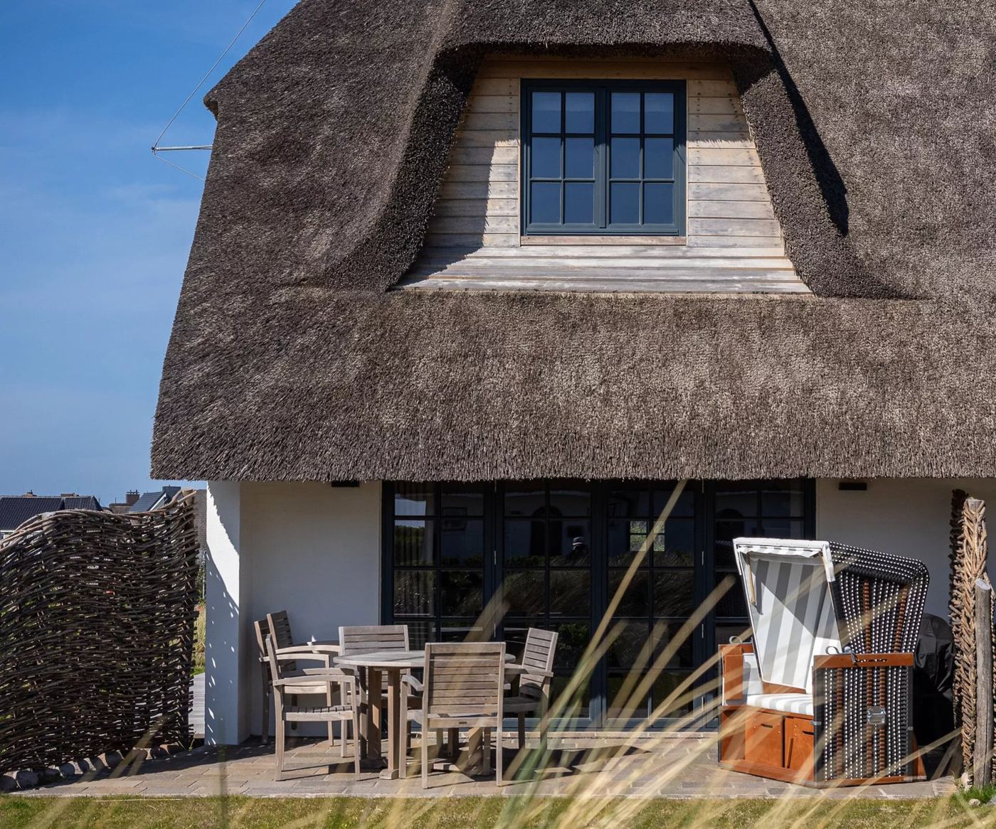 Strandkorb auf der Terrasse eines Reetdachhauses